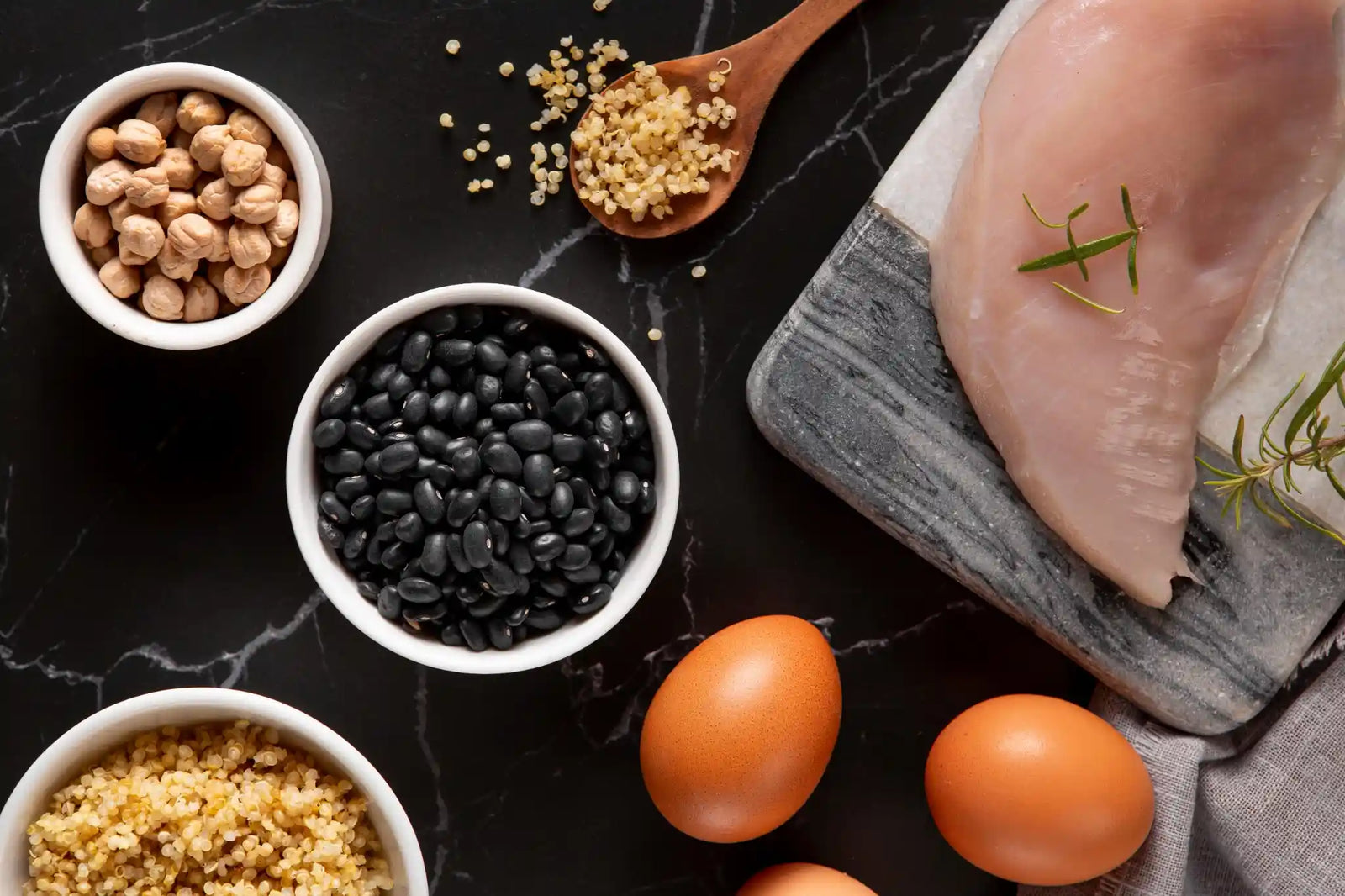 A countertop with a spread of high-protein foods such as eggs & meat representing how much protein should an athlete eat.